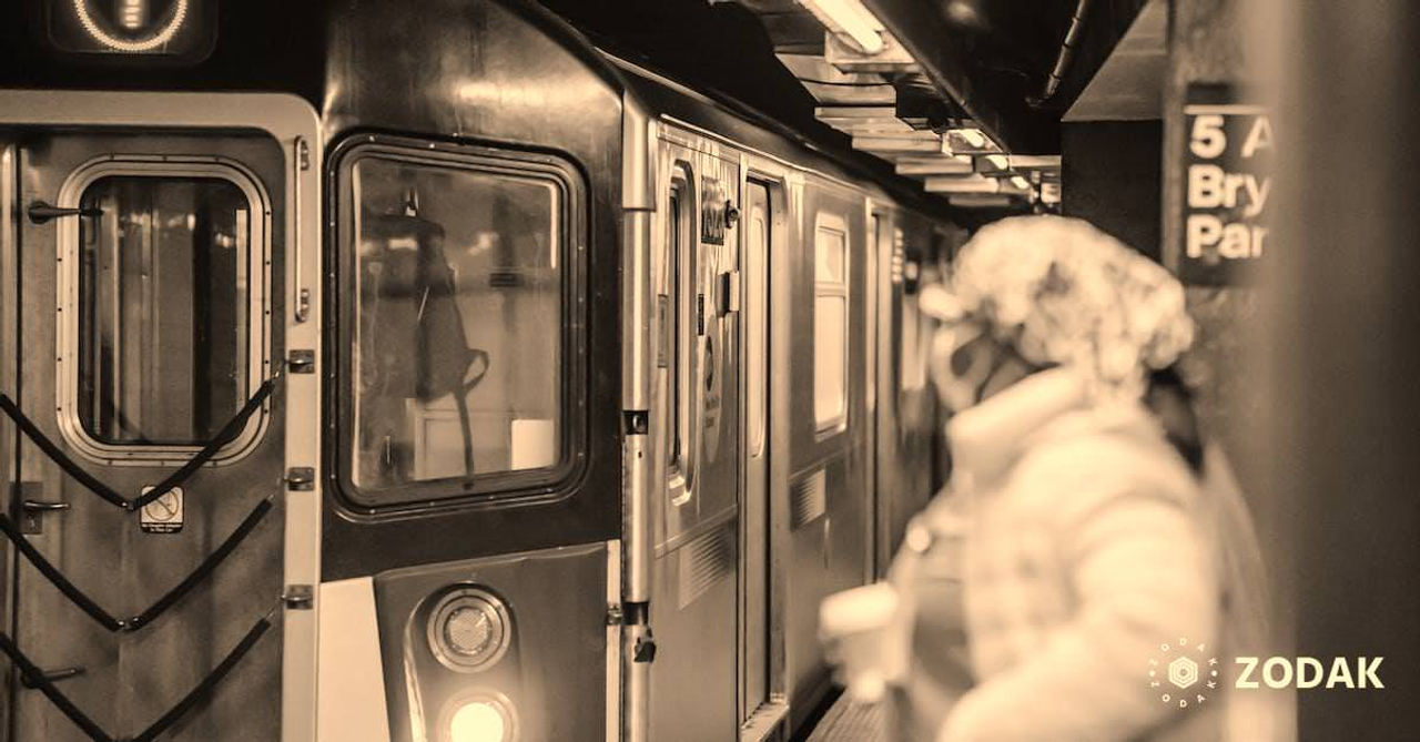 Unrecognisable female in medical uniform coat and with paper cup waiting for train arriving on subway platform