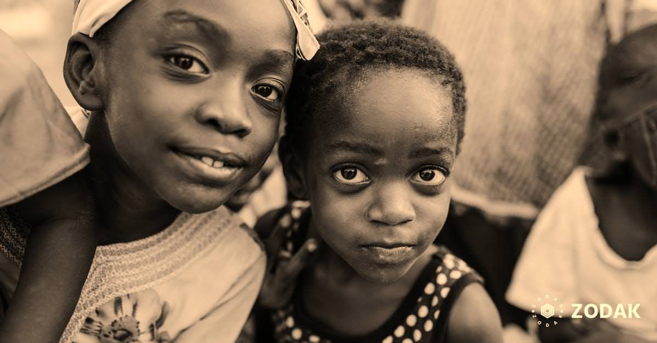 Black and white glad children in casual clothes standing on authentic town street and looking at camera with curiosity