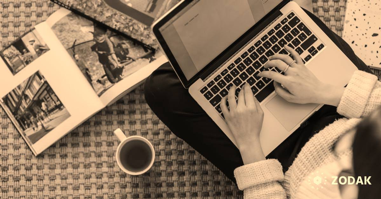 Crop young businesswoman using laptop while drinking tea at home