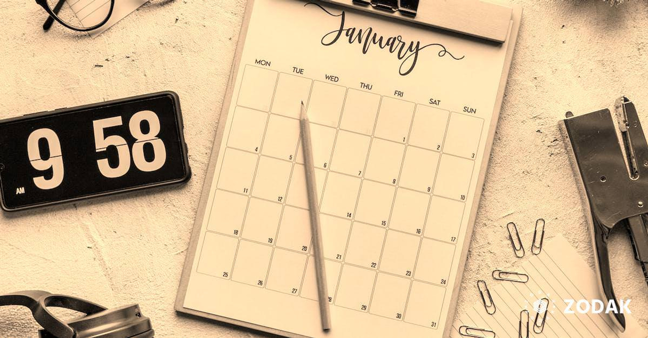 Top view composition of clipboard with calendar and pencil placed on desk amidst stationery and eyeglasses