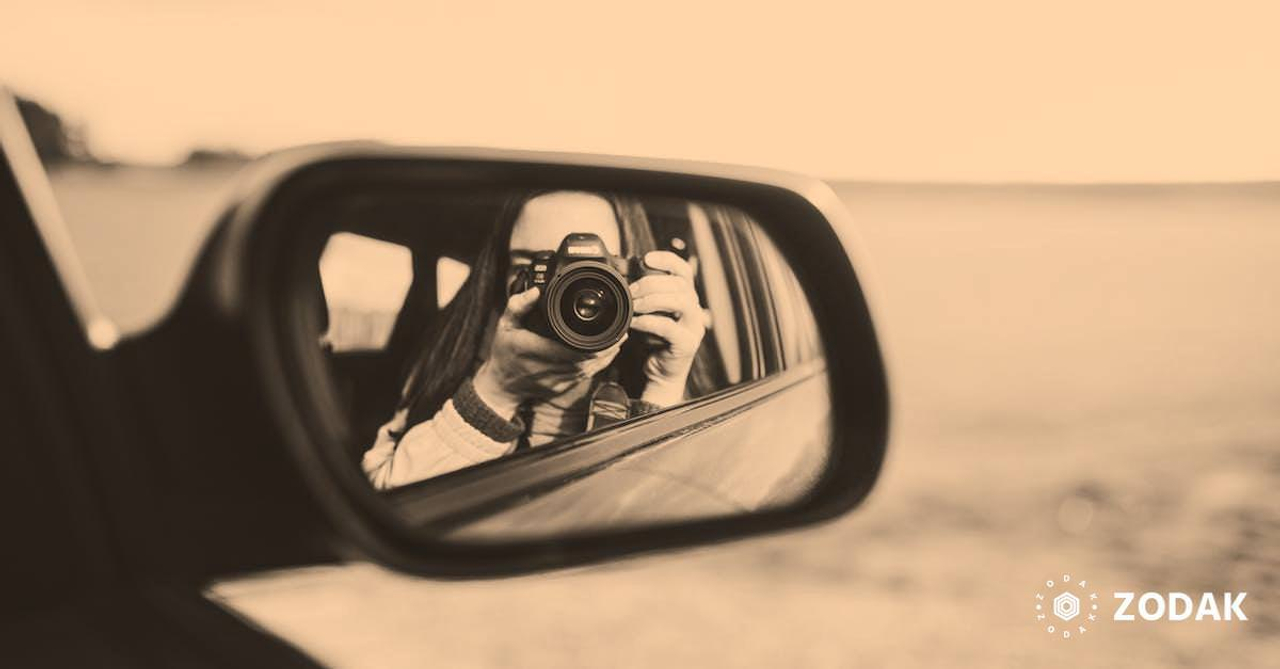 Unrecognizable female photographer taking photos and reflecting in rear window