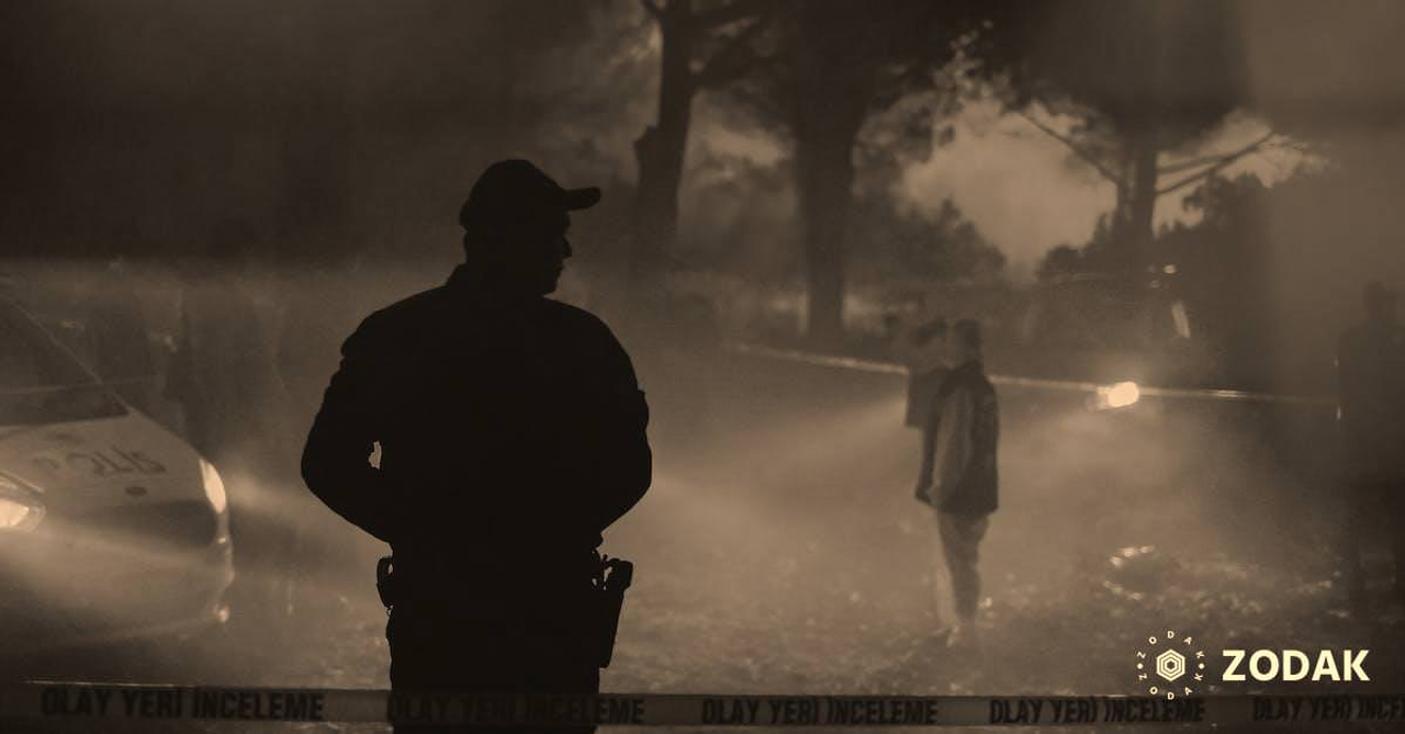 Silhouette of policeman and investigators standing behind crime scene boundary tape at night in forest