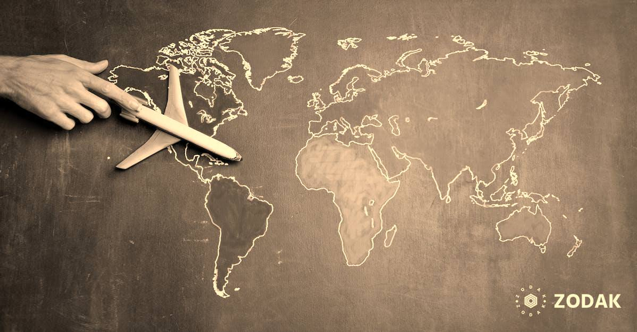 Top view of crop anonymous person holding toy airplane on colorful world map drawn on chalkboard