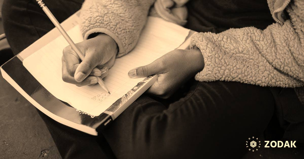 Clever diligent ethnic child doing homework on sheet of paper